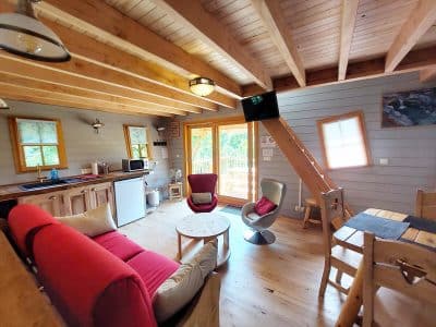 Cabane en bois cosy avec salon lumineux et vue sur la nature en Auvergne-Rhône-Alpes.