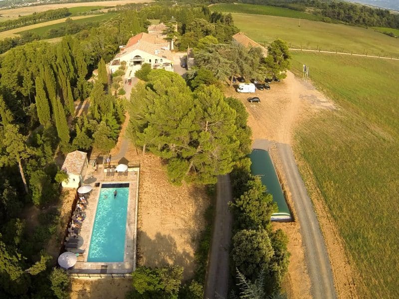 Charmante villa avec piscine, entourée de verdure et de champs ensoleillés.