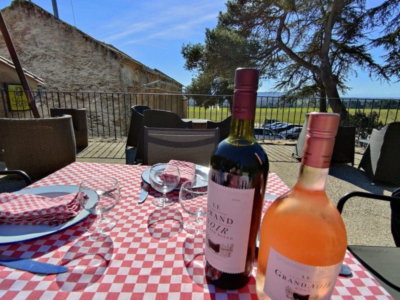 Table en extérieur avec vin rouge et rosé, vue sur la campagne, ambiance conviviale.