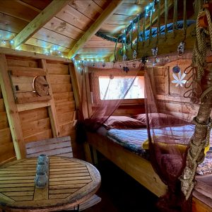 Cabane en bois cosy avec lit douillet et guirlandes lumineuses. Parfait pour se ressourcer.