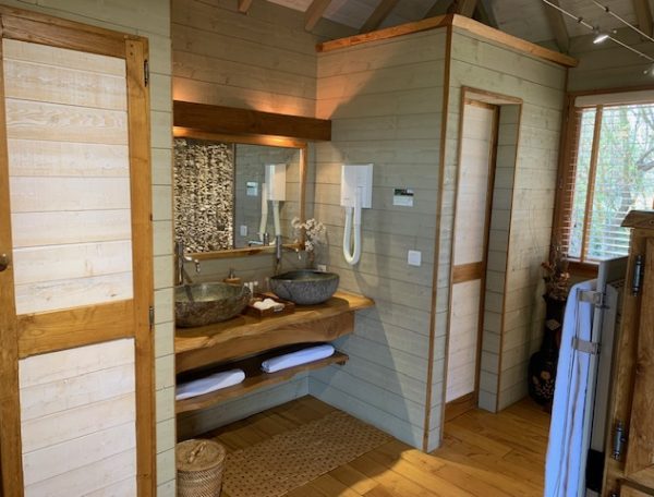 Salle de bain dun chalet en bois, avec vasques en pierre et lumière naturelle.
