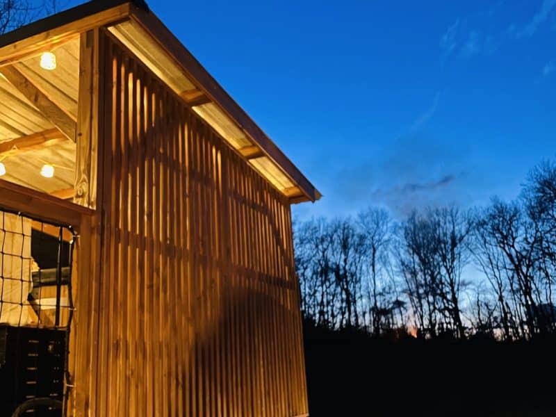 Cabane en bois avec éclairage chaleureux sous un ciel étoilé.