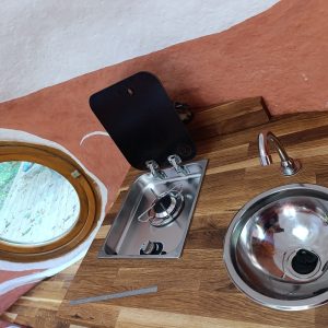 Hébergement insolite en Limousin : cuisine équipée avec évier et fenêtre ronde.
