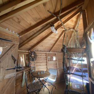Cabane en bois avec décorations naturelles et éclairage doux, ambiance chaleureuse.