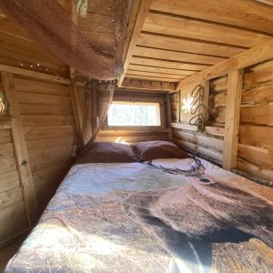 Cabane en bois à Midi-Pyrénées avec un lit décoré dun motif de cerf.