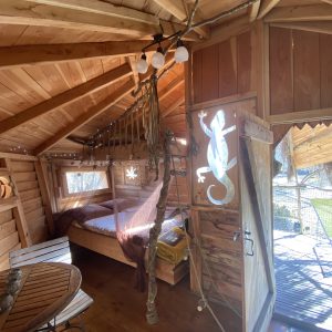 Cabane en bois dans les Midi-Pyrénées, avec lit douillet et décor naturel.