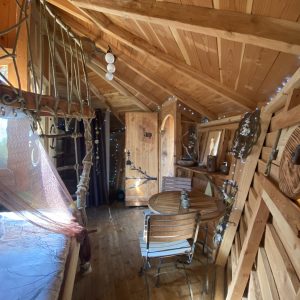 Cabane en bois avec intérieur chaleureux, décoré de guirlandes lumineuses.