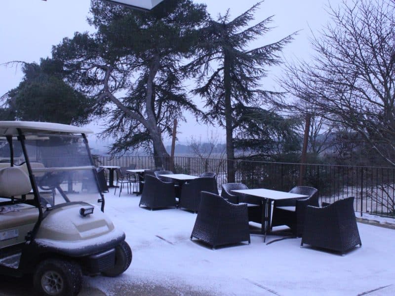 Hébergement en chalet avec terrasse, entouré darbres sous la neige.