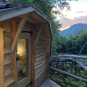 Cabane en bois perchée, offrant une vue sur les montagnes et la nature environnante.