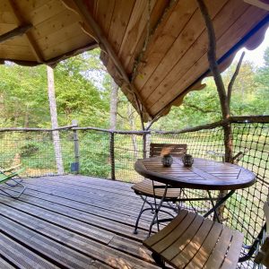 Cabane perchée en bois avec terrasse en bois et vue sur la nature environnante.