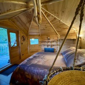 Cabane en bois chaleureuse avec lit douillet et vue sur la nature environnante.