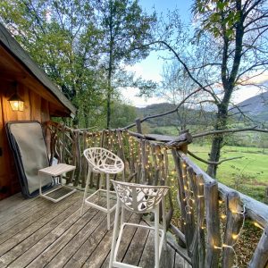 Cabane perchée en Midi-Pyrénées avec terrasse en bois et vue sur la nature.