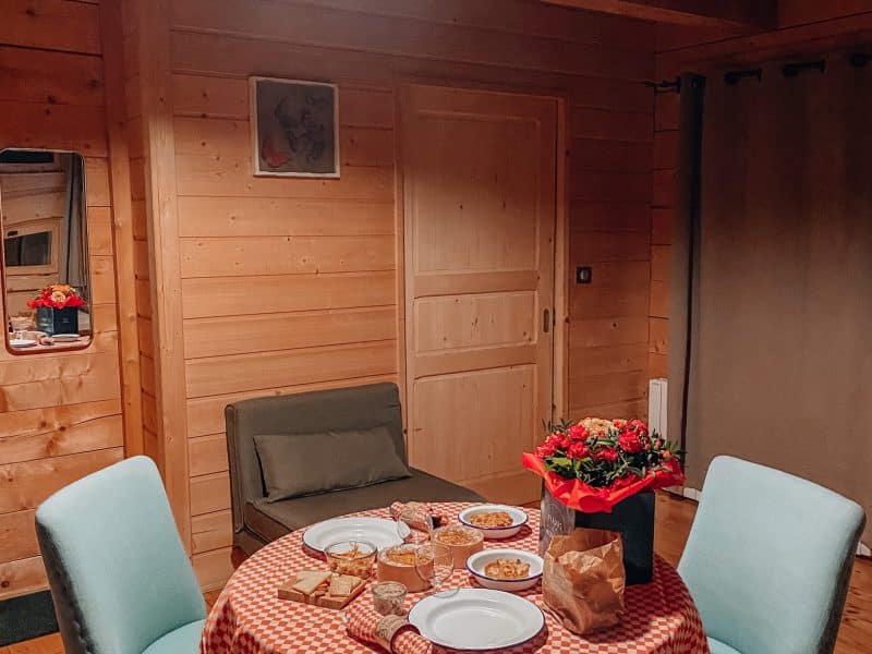 Chalet en bois chaleureux avec une table dressée et des fleurs au centre.