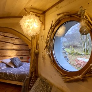 Hébergement insolite en Midi-Pyrénées : cabane en bois avec fenêtre ronde et déco chaleureuse.