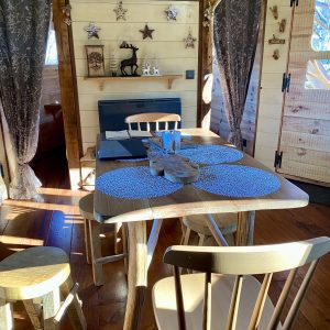 Intérieur chaleureux dun hébergement insolite en Midi-Pyrénées, avec table en bois et décor cosy.