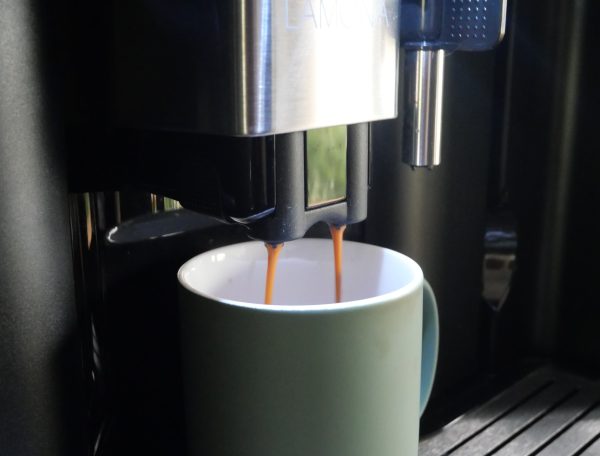 Machine à café moderne dans un hébergement, préparant un café dans une tasse verte.