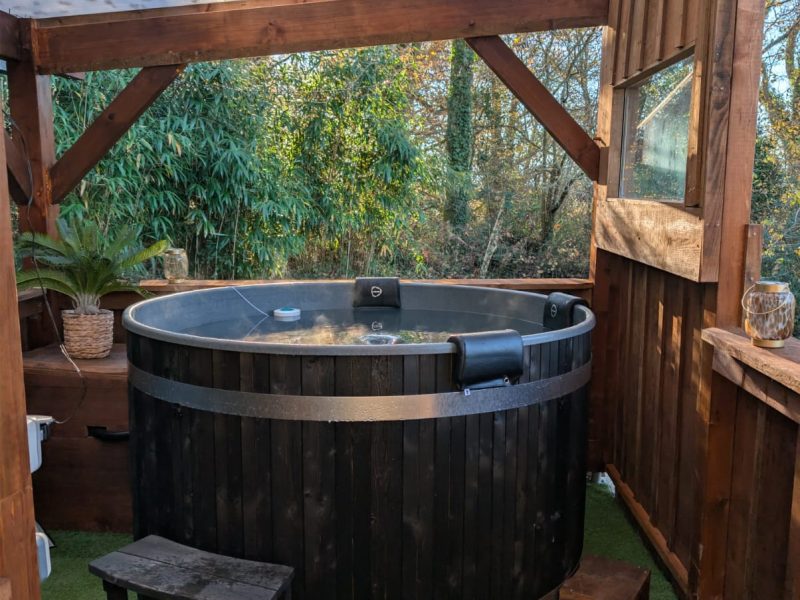 Hébergement insolite en Aquitaine avec un jacuzzi en bois sous une pergola.