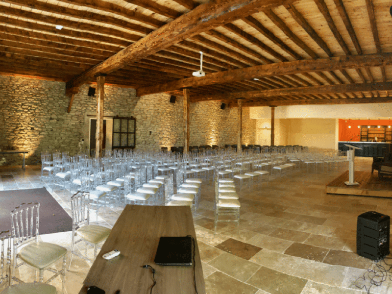 Salle de séminaire dans un gîte, avec murs en pierre et chaises transparentes.