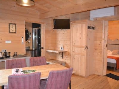 Chalet en bois chaleureux avec cuisine, table à manger et décoration cosy.