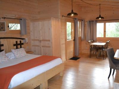 Chalet en bois chaleureux avec lit douillet et vue sur la nature environnante.