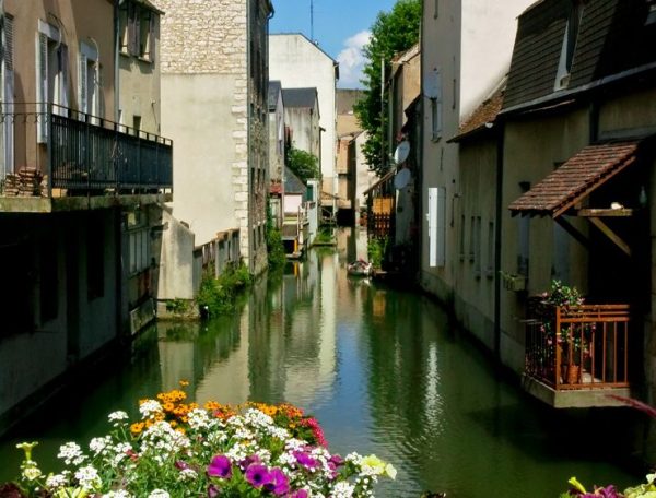 Charmant gîte au bord dun canal, avec des fleurs colorées en façade.