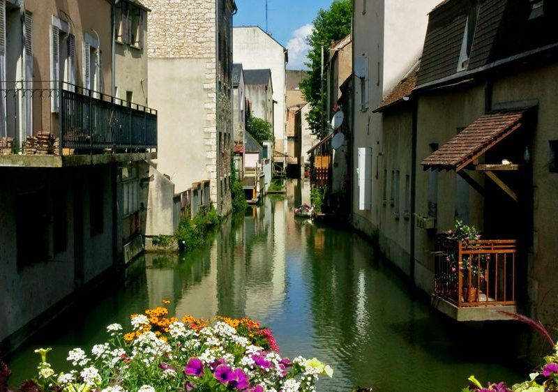 Charmant gîte au bord dun canal, avec des fleurs colorées en façade.