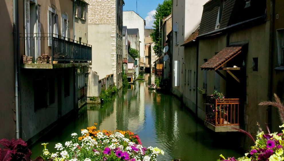 MONTARGIS 1 Hébergement insolite en bord de canal, avec fleurs colorées et maisons typiques.
