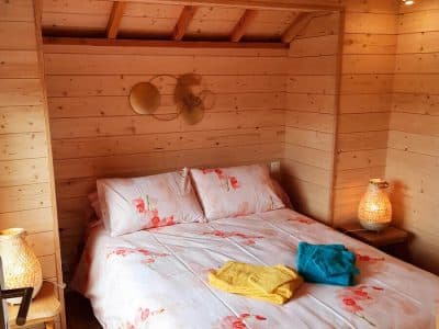 Chalet en bois chaleureux avec lit douillet et décoration florale accueillante.