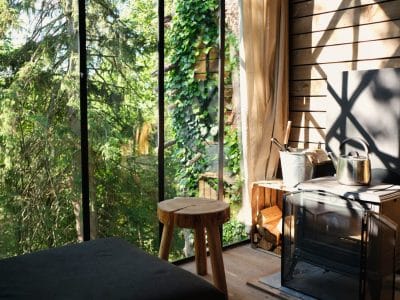 Cabane en bois avec grandes fenêtres, vue sur la nature verdoyante en Wallonie.