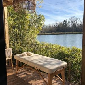 Cabane au bord de leau avec table de massage et vue sur la rivière.