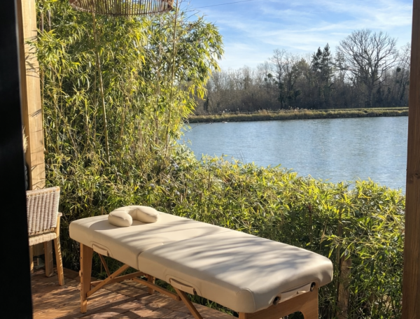 Cabane au bord de leau avec table de massage et vue sur la rivière.