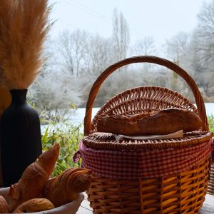 Panier en osier avec viennoiseries, vue paisible sur la nature hivernale.
