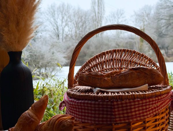 Panier en osier avec viennoiseries, vue paisible sur la nature hivernale.