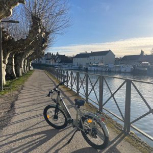 Vélo électrique stationné le long dun chemin paisible près dun hébergement au bord de leau.