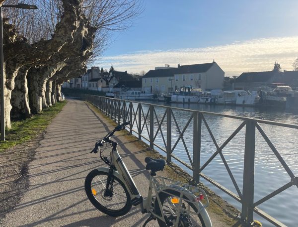 Vélo électrique stationné le long dun chemin paisible près dun hébergement au bord de leau.