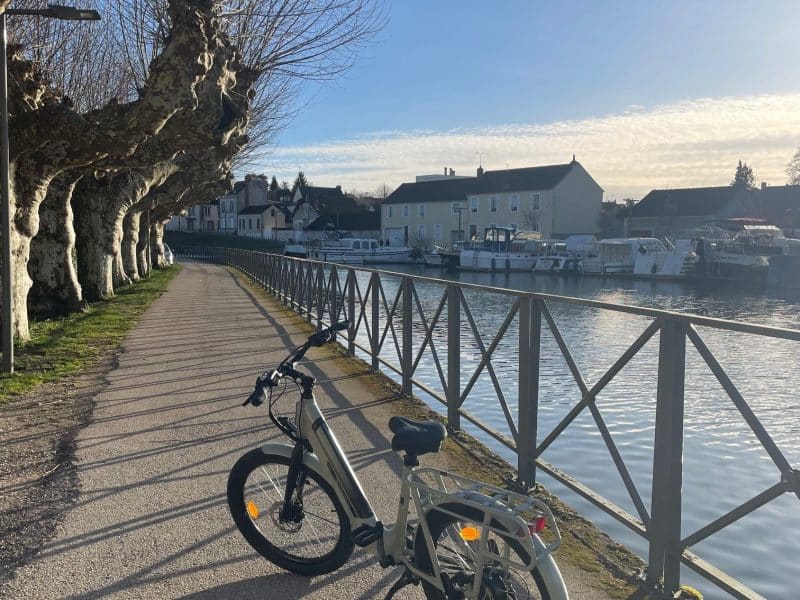 Vélo électrique stationné le long dun chemin paisible près dun hébergement au bord de leau.