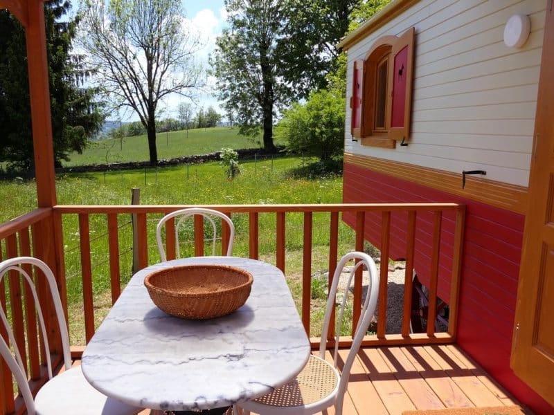 Charmante roulotte avec terrasse en bois et vue sur la nature verdoyante.