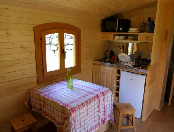 Chalet en bois chaleureux avec cuisine équipée et table à carreaux.