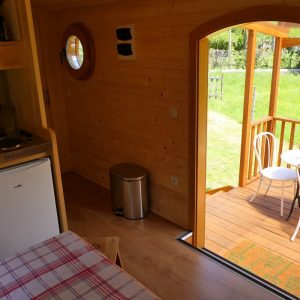 Intérieur dun chalet en bois avec vue sur une terrasse ensoleillée.