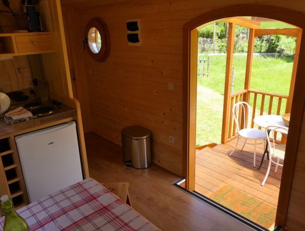 Intérieur dun chalet en bois avec vue sur une terrasse ensoleillée.