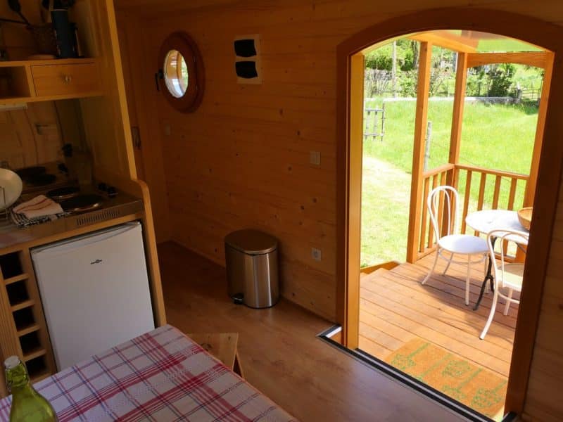Intérieur dun chalet en bois avec vue sur une terrasse ensoleillée.