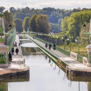 Pont élégant sur un canal, entouré de verdure, idéal pour un séjour paisible.