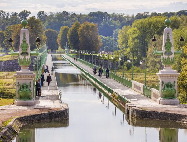 Pont élégant sur un canal, entouré de verdure, idéal pour un séjour paisible.