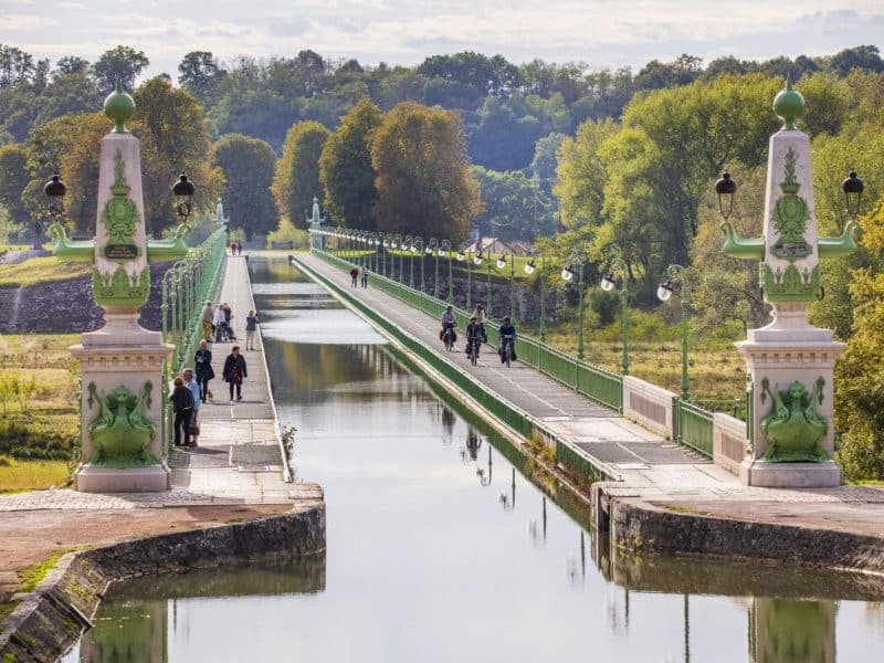 Pont élégant sur un canal, entouré de verdure, idéal pour un séjour paisible.