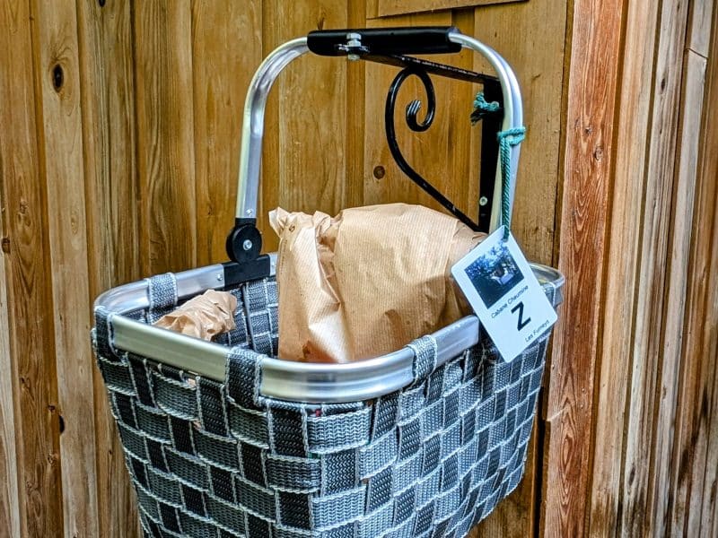 Panier en osier suspendu à un mur en bois, accueillant des produits locaux.