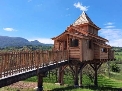 Cabane perchée en bois avec balcon, offrant une vue imprenable sur les montagnes.