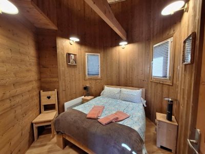 Chalet en bois chaleureux avec lit douillet et lumière douce, idéal pour un séjour cocooning.