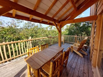 Cabane en bois avec terrasse ensoleillée et mobilier en bois naturel.
