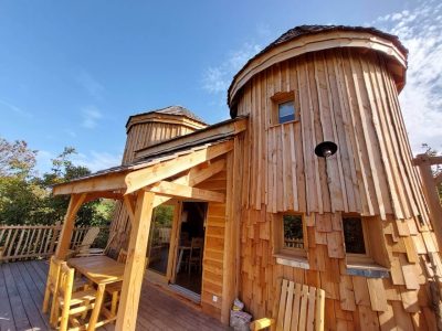 Cabane en bois à Auvergne-Rhône-Alpes avec un toit en ardoise et terrasse ensoleillée.