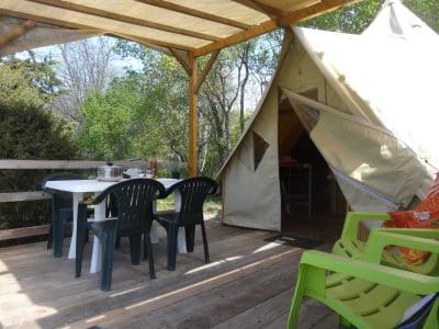 Tente safari spacieuse avec terrasse en bois et mobilier extérieur coloré.